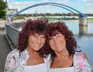 29 May 2024, Brandenburg, Frankfurt (Oder): The well-known twins from Frankfurt (Oder), Heike Guderian (l) and Heidi Kapuste, stand by the River Oder with the city bridge in the background. Photo: Patrick Pleul/dpa