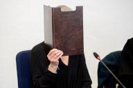 30 May 2024, Lower Saxony, Oldenburg: The defendant sits in a courtroom in the district court before the start of the trial and holds a file cover in front of her face. The defendant is accused of killing her husband with a sword in Damme on March 5, 2024 in a state of incapacity or significantly reduced culpability. Photo: Hauke-Christian Dittrich/dpa