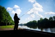 30 May 2024, Lower Saxony, Oldenburg: An angler stands in the shade on the banks of the Hunte. Photo: Sina Schuldt/dpa