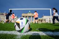 26 May 2024, Berlin: Children play soccer on the artificial turf in front of the Brandenburg Gate with the giant soccer goal behind the official soccer for the European Championship with the inscription UEFA Euro 2024. Photo: Kay Nietfeld/dpa