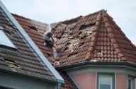 30 May 2024, North Rhine-Westphalia, Hagen: A roofer works on a partially covered roof. After a strong wind - probably a tornado - in Hagen, the clean-up work continued on Thursday. Photo: Bernd Thissen/dpa