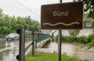 01 June 2024, Bavaria, Günzburg: A car drives over the Günz, whose water level almost reaches the road. Flooding is expected after the heavy rainfall of the last few days. Photo: Stefan Puchner/dpa