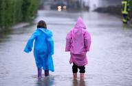 01 June 2024, Bavaria, Dasing: Two children in rubber boots walk across a flooded street in Dasing in the Swabian district of Aichach-Friedberg. Photo: Sven Hoppe/dpa