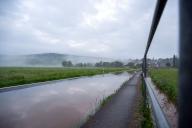 02 June 2024, Bavaria, Busendorf: A road is flooded, the village of Gleusdorf (Haßberge district, Lower Franconia) can be seen in the background. The Itzgrund is flooded, the Schenkenau gauge has reached level 3. Roads are closed, the flooded area reaches as far as the first houses. Photo: Pia Bayer/dpa