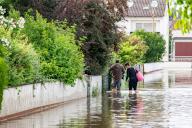 02 June 2024, Bavaria, Baar-Ebenhausen: A woman and a man walk through a flooded street. Extreme continuous rain in Bavaria, a state of disaster applies in three districts. Photo: Armin Weigel/dpa