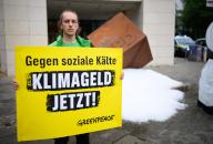 03 June 2024, Berlin: An activist holds a sign reading "Against social coldness - climate money now!" during a protest action by the environmental protection organization Greenpeace in front of the SPD headquarters. Greenpeace activists poured out about a ton of ice in front of the SPD headquarters in Kreuzberg and erected a frozen "S" from the SPD logo to demonstrate for the introduction of the climate money. Photo: Bernd von Jutrczenka/dpa