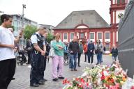 03 June 2024, Mannheim: Numerous people, including police officers, stand in front of candles and flowers placed near the scene of Friday
