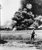 Burning oil tanks and cars left by retreating Dutch in Tandjong, Java. Ca. Feb.-Mar. 1942. World War 2. (BSLOC_2014_10_137)