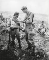U.S. soldier of lights a cigarette for a former enemy guard. They are at a surrender conference between American and Japanese officers on a Sierra Madre mountain top in Northern Luzon, Philippines. Aug. 22, 1945. World War 2. (BSLOC_2014_10_128)