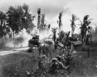 U.S. Troops take cover behind advancing tanks while moving up on Japanese positions. March 18, 1945. Pansy Island, Philippines, World War 2.. (BSLOC_2014_10_111)