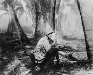 U.S. Soldiers crouch on palm fronds as they push ahead on Makin Atoll in the Gilbert Islands. Nov. 20-23, 1943. U.S. ground casualties were 66 killed and 152 wounded against 395 Japanese killed and 3 captured. World War 2. (BSLOC_2014_10_101)