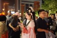 A woman in ancient-style costumes checks her phone during walking in a street in Xi\'an in northwest China\'s Shaanxi province Thursday, May 02, 2024