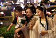 Women in ancient-style costumes check their photos during walking in a street in Xi\'an in northwest China\'s Shaanxi province Thursday, May 02, 2024