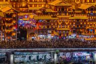 Tourists walk on a bridge beside the illuminated Hongyadong cluster of traditional looking buildings in southwest China\'s Chongqing Municipality Friday, May 03, 2024
