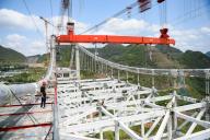 Workers labor at the construction site of a 1,600-meter-long suspension bridge in Xingyi city in southwest China\'s Guizhou province Monday, May 06, 2024