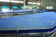 People work on the bottling line at a plant of bottled water in Yuexi county in central China