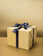 Wrapped gift with gold wrapping paper and black ribbon against gold background