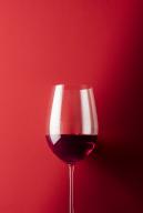Glass of red wine against red background