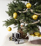Presents under Christmas tree decorated with yellow ornaments and silver pig