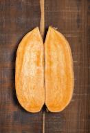Two halves of sweet potato on wood background