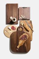 High angle view of an assortment of wood cutting boards with prepared meats, cheese, bread and crackers on white background