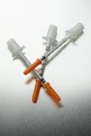 Three medical syringes with orange caps