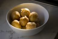 White bowl filled with small yellow Yukon potatoes in golden, late afternoon sunlight