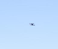 Low angle view of small drone hovering in mid-air against a blue sky
