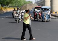 NOIDA, INDIA - MAY 12: Commuters using umbrella to protect them from the hot summer day at sector 38, on May 12, 2024 in Noida, India. (Photo by Sunil Ghosh/Hindustan Times 