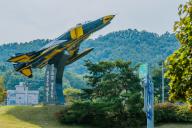 Military fighter jet in flying orientation mounted on stand on permanent display at entrance to city in South