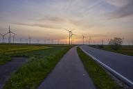Wind turbines with country road and cycle path in front of setting sun and sunset near Bordelum, Nordfriesland district, Schleswig-Holstein, Germany