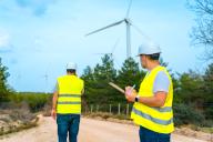 Technicians inspecting wind turbines in a green energy park talking to the mobile and taking