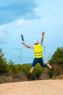 Worker jumping and raising arms in a path in a green energy
