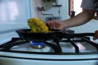Person making a potato omelet in a frying pan on a butane