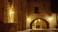 Night scene of a person walking under the arch of an illuminated building, night shot, Rhodes Old Town, Rhodes, Dodecanese, Greek Islands, Greece