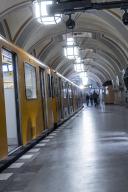 A yellow underground train stops at an arched platform underground, Heidelberger Platz, Berlin, Germany