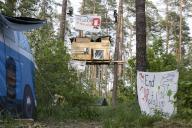Two people swinging over a tree house in the occupied forest section Tesla Stop . In the foreground a banner End CARpitalism . The occupation of the forest is intended to demonstrate against the imminent clearing for the planned expansion of the 