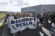 Participants with banner Disrupt Tesla in front of the Tesla Gigafactory at the demonstration Water. Forest. Justice against the expansion of the Tesla Gigafactory in Grünheide near Berlin, 11.05