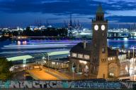 St-Pauli-Landungsbrücken, Landungsbrücken in the evening at blue hour, traces of light from passing ships, tide gauge tower with clock, behind it cranes in Hamburg harbour, Hamburg, Germany
