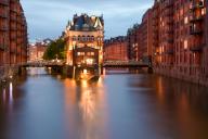 Warmly illuminated warehouse district in the evening light with water reflections and a moated castle, moated castle, part of the Unesco World Heritage Site, Hamburg, Germany