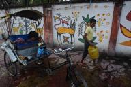 Cycle rickshaw rider washing his engine in the street, mural paintings, Hazaribagh, Jharkhand, India