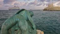 A damaged sculpture looks out over the sea and a fortress during a dramatic sunset, sky exchanged, sculpture Sleeping Eros, cruise ship, Fort of Saint Nikolaos, harbour area, Rhodes Town, Rhodes, Dodecanese, Greek Islands, Greece