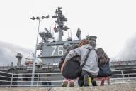 A family watches the aircraft carrier USS Ronald Reagan depart the U.S. Navy