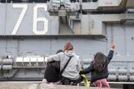 A family watches the aircraft carrier USS Ronald Reagan depart the U.S. Navy