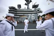 Crew members of the aircraft carrier USS Ronald Reagan takes a photo on the flight deck before departing the U.S. Navy