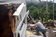 Sammy Gibson uses a chainsaw to cut apart a house that came to rest on a bridge near the Whitesburg Recycling Center in Letcher County, Kentucky, on Friday, July 29, 2022. (Ryan C. Hermens/Lexington Herald-Leader/TNS