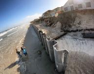 Beachgoers walk past a new, reinforced fiberglass seawall in the process of being installed, south of Toronita Avenue Beach Park in Wilbur-By-The-Sea, Florida, Friday, Dec. 2, 2022. The southern Volusia coastline was devastated by significant beach erosion from Hurricane Ian and Tropical Storm Nicole, causing millions in damage to oceanfront properties. (Joe Burbank/Orlando Sentinel/TNS