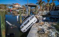 A 2003 Ford Mustang hangs off a seawall behind a house in Fort Myers Beach, Florida, on Oct. 26, 2022. The car was carried away in Hurricane Ian s storm surge a month earlier. (Pedro Portal/Miami Herald/TNS