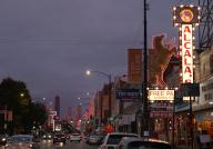 The city skyline glows a golden hue as the Alcalas Western Wear sign lights up, as the sun sets over Chicago Avenue near Ashland Avenue on Oct. 18, 2022