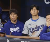 Shohei Ohtani (R) of the Los Angeles Dodgers and his interpreter Ippei Mizuhara watch Major League Baseball